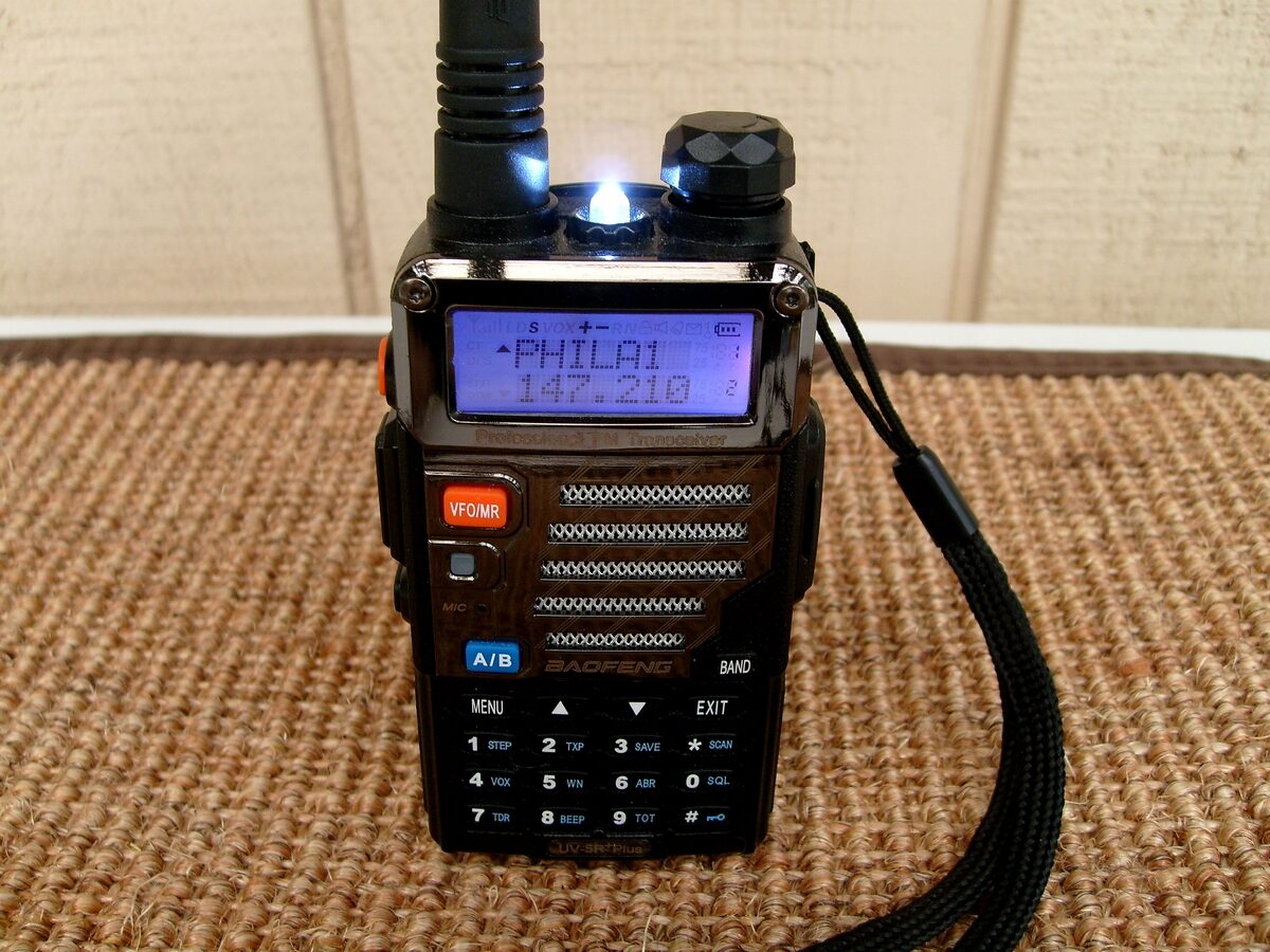 Baofeng UV-5R dual-band handheld ham radio with the display lit, programmed to a 2 m repeater channel