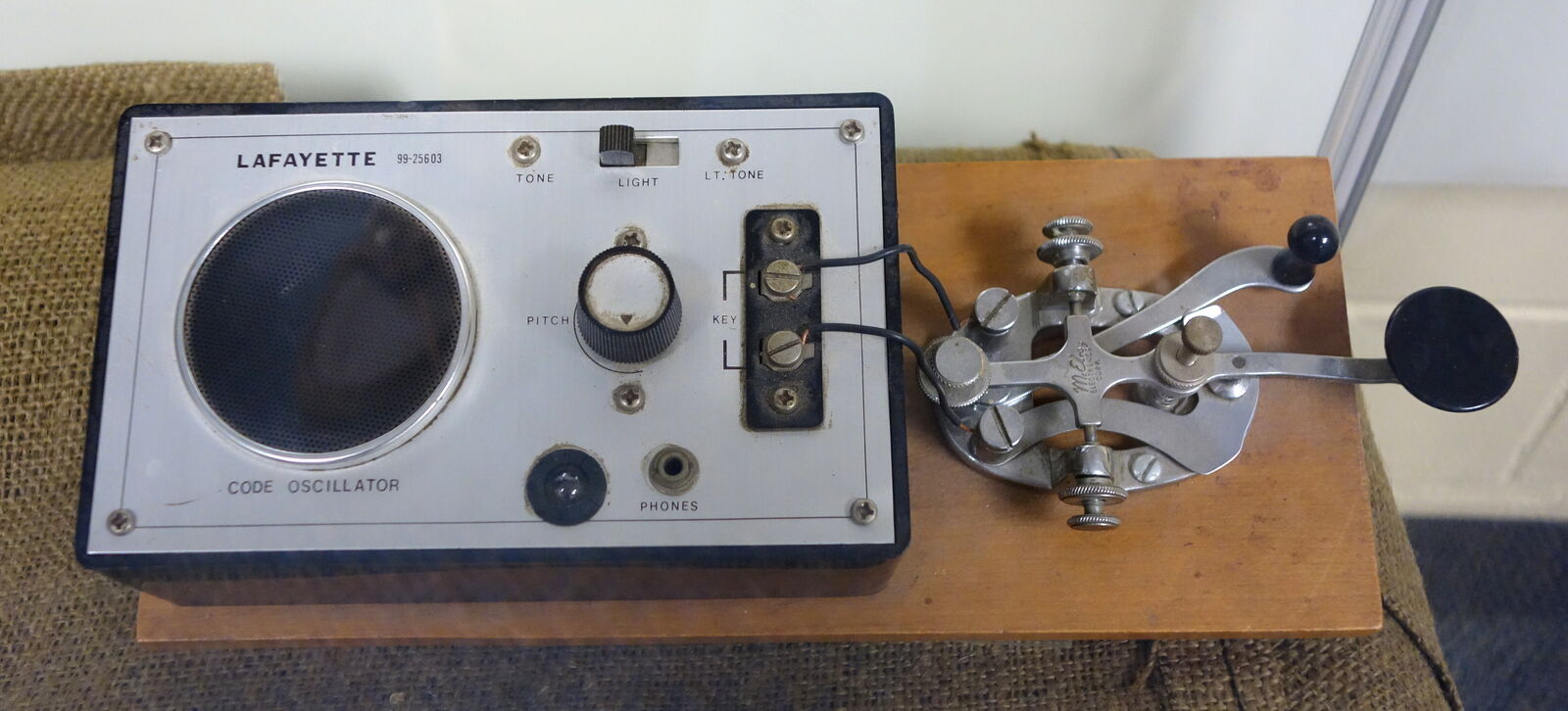 Vintage chrome Morse code straight key wired to a code practice oscillator on a wooden base