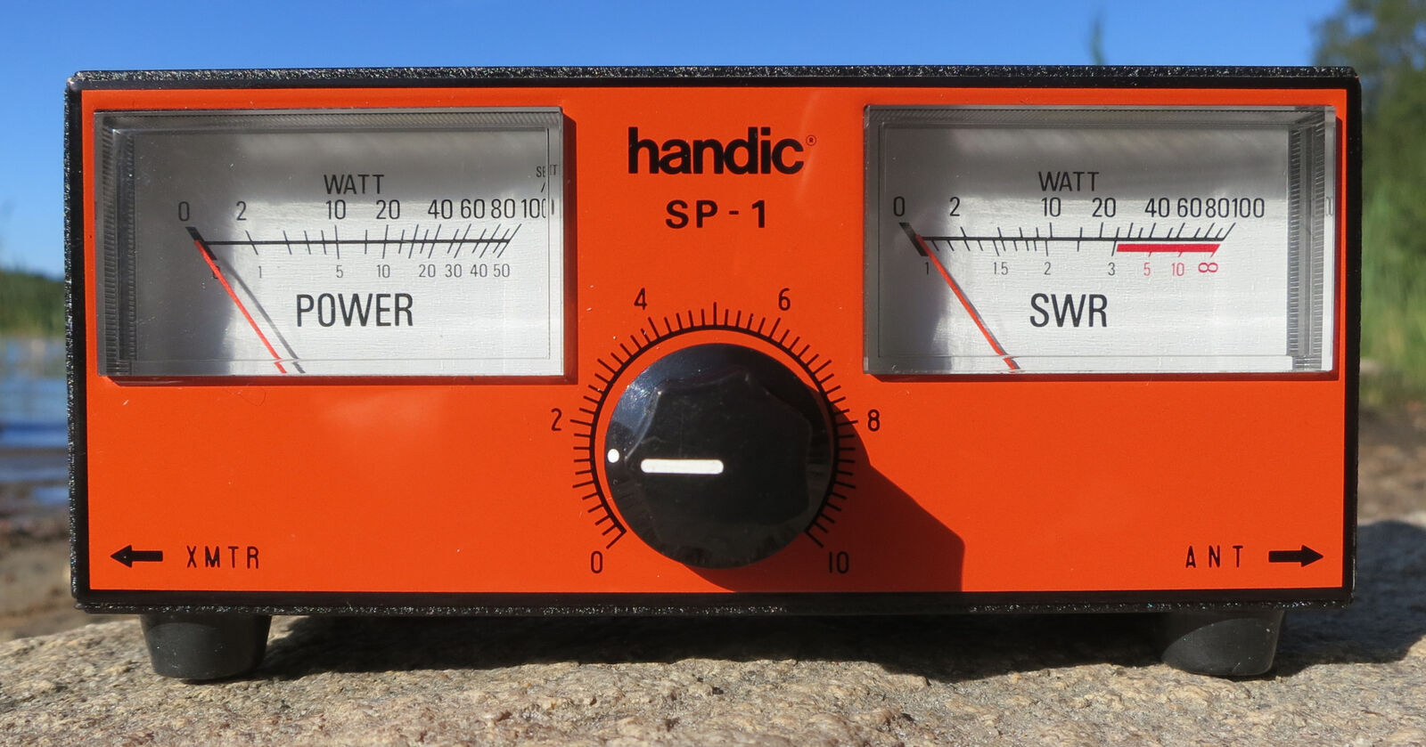 Orange 1970s SWR and power meter with twin analog needle displays photographed outdoors